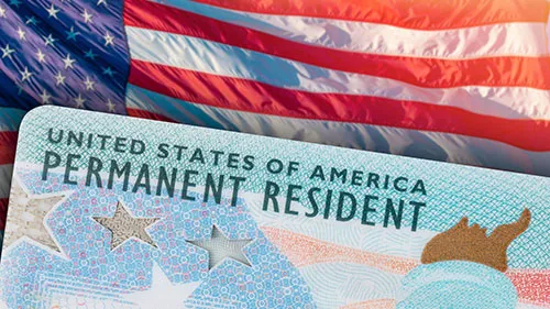 Permanent resident card in front of U.S. flag.