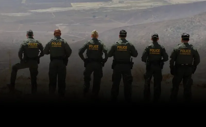 Border Patrol Agents look over the border from a hilltop.